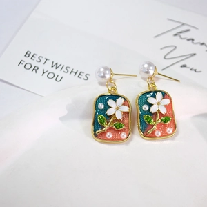 Detail of French vintage gold earrings with enamel floral pendant and pearl studs
