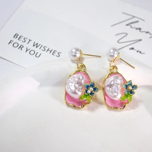 Close-up of French vintage drop earrings with pink enamel flowers and baroque pearls