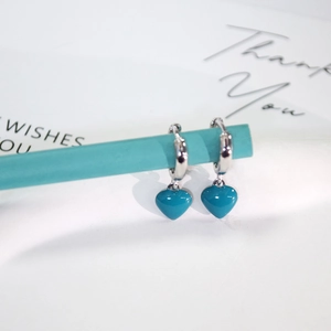 Silver alloy hoop earrings with teal heart enamel charms on a gift card display