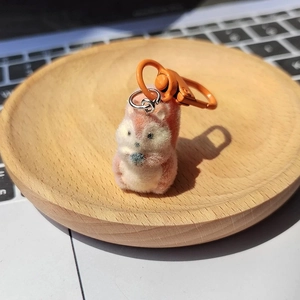 Cute pink flocked squirrel keychain with blue nut accessory on a wooden tray