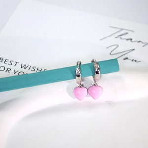 Pink heart drop earrings in silver finish hanging on a teal bar for sweet fashion style