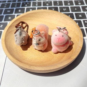 Detailed view of flocked animal keychains in grey orange and pink on a wooden tray