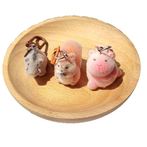 Three cute flocked animal keychains including rhino and squirrel on a wooden tray