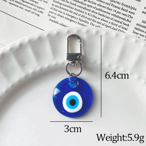 Blue resin Evil Eye keychain with silver lobster clasp on white tray, 6.4cm x 3cm