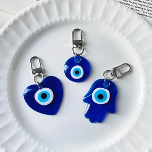 Detailed close-up of blue resin Evil Eye Hamsa and heart charms on a decorative white plate