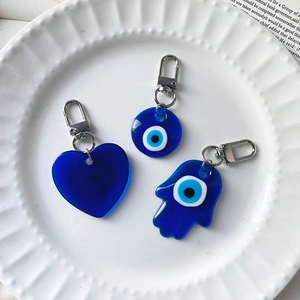 Detailed view of resin Evil Eye charms in heart, round and Hamsa shapes with silver clasps