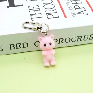 Detailed macro view of pink flocked kitten pendant with silver lobster clasp on green background