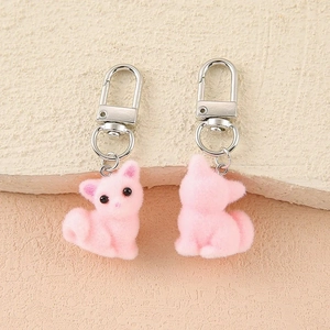 Close-up of two pink flocked cat keychains with silver alloy lobster clasps on stone background