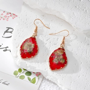Detail of red resin drop earrings with dried flowers and gold wire wrapped edges