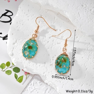 Detail view of handmade resin drop earrings with dried flowers and copper wire wrapping