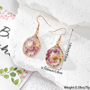 Detailed size view of teardrop resin earrings with purple and yellow dried flowers