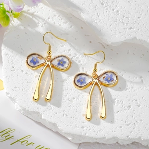 Elegant gold bow earrings with blue dried flowers and gold foil in resin, long drop style