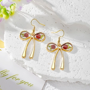 Golden bow earrings with red roses in transparent resin on white stone base