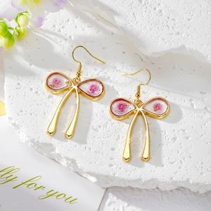 Elegant gold bow earrings with real pink dried rose and gold foil inside a clear pendant