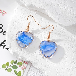 Detailaufnahme herzförmiger blauer Harz-Ohrringe mit goldener Kupferdraht-Einfassung
