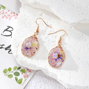 Detail of handmade resin earrings with dried flowers and copper wire wrap detailing