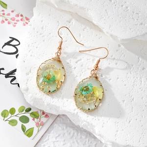 Detail of handmade resin earrings with dried flowers and twisted gold wire trim