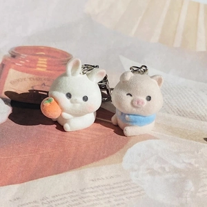 Detail of cute flocked animal keychains featuring a white bunny and pink pig on a magazine