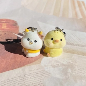Detailed view of soft flocked duck and cow keychains with silver metal lobster clasps