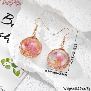 Détails de boucles d'oreilles en résine avec fleurs séchées, fil doré et crochets en acier