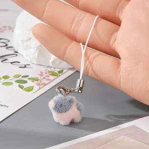 Close-up of soft pink and grey flocked bird keychain with plush texture and white lanyard