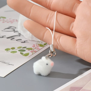 Close-up of white plush bunny keychain with soft fur detail held in hand as a cute accessory