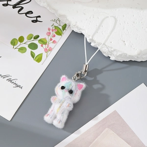 Detail of a white flocked kitten keychain with colorful paint splatters and silver clasp