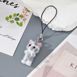 Close-up of a cute flocked resin cat keychain with soft gray and white texture details