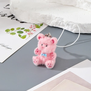Close-up of a cute pink flocked bear keychain with blue bowtie and silver metal attachment