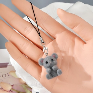 Detail view of a gray flocked resin bear charm with a black lanyard and silver clasp