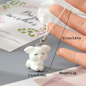 Close-up of white flocked animal keychain with silver clasp and braided strap details