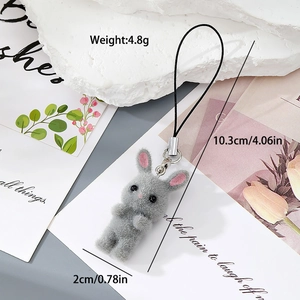 Detail of grey flocked rabbit keychain with size and weight specs on a floral background