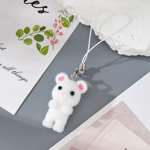 Macro detail of a white flocked animal charm featuring a plush texture and silver metal clip