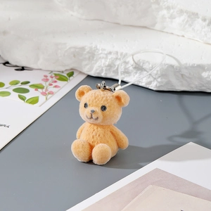 Detailed close-up of orange flocked resin bear pendant with soft texture and white rope loop
