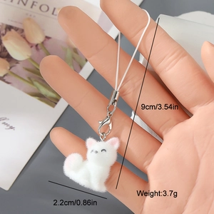 Close-up of a white flocked resin cat charm with a metal clasp and white lanyard