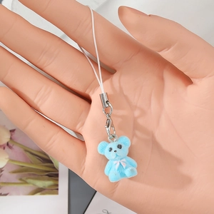 Detailed view of a cute blue flocked bear keychain accessory held on a model's hand