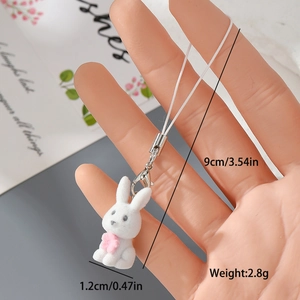 Handheld shot of a mini white flocked rabbit charm with pink flowers for bags and phones