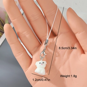 Detail view of a mini white flocked dog charm with a lobster clasp on a woven lanyard