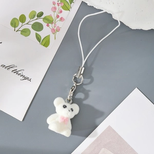 Detail of a white flocked bear keychain with pink bow and silver metal lobster clasp