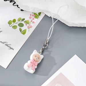 Close-up of white flocked kitten charm with a pink bow on a refined stone backdrop