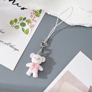 Close-up of a white flocked bear keychain with a pink bow and silver metal clasp