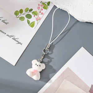 Close-up of a white flocked bear keychain with a pink bow and white braided lanyard