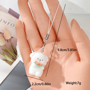 Close-up of white flocked bear charm with lobster clasp held to show size and texture