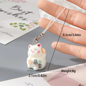 Makroaufnahme vom weißen beflockten Winkekatze-Anhänger mit Kanji und Metallverschluss
