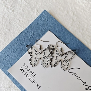 Close-up of butterfly acrylic earrings with calligraphy print and stainless steel hooks