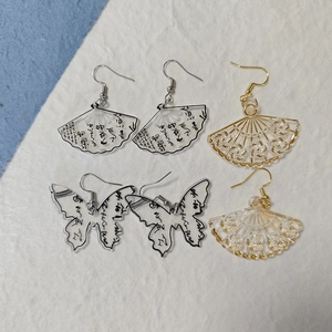 Detail view of acrylic fan and butterfly earrings with Chinese calligraphy patterns
