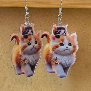 Detail of acrylic cat earrings featuring orange tabby and cherry blossom print
