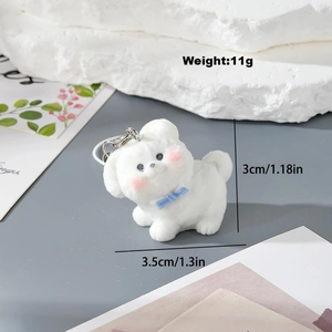 Cute white flocked puppy keychain with blue bow and silver ring on decorative stone