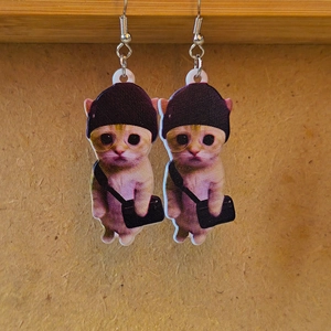 Detailed view of fun acrylic earrings featuring cartoon cats with hats and bags