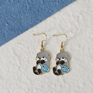 Cute cartoon sea lion earrings with blue fish detail on minimalist background